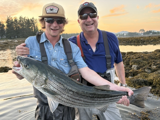 Anglers with a striped bass at sunset